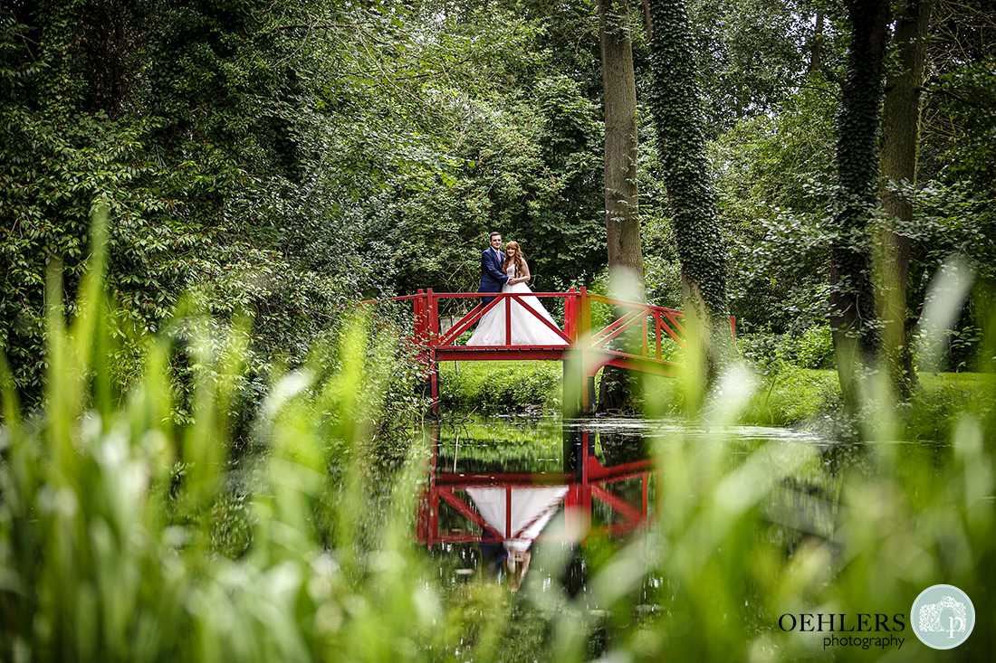 Photograph of the bride and groom on the red bridge at Thrumpton Hall.