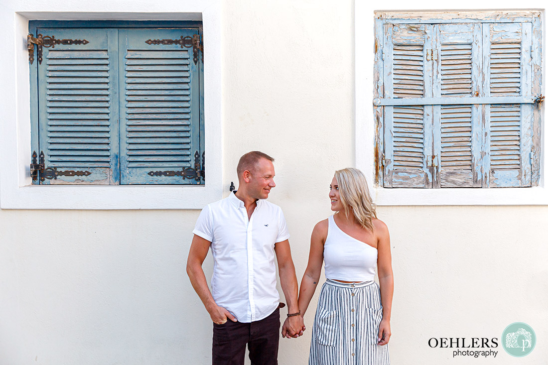 Santorini Wedding Photographers - Bride and Groom in middle of blue, shuttered windows on either side.