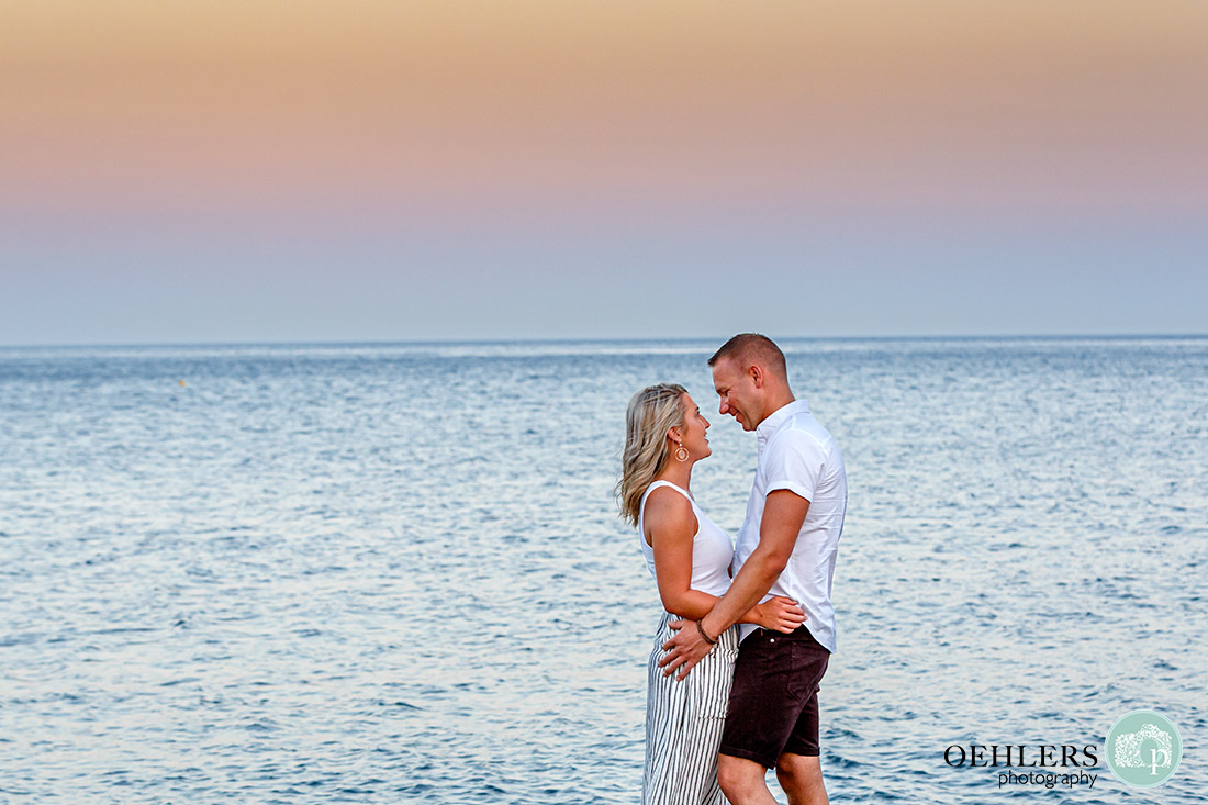 A glowing sky after sunset in the background as the couple gaze into each others eyes.