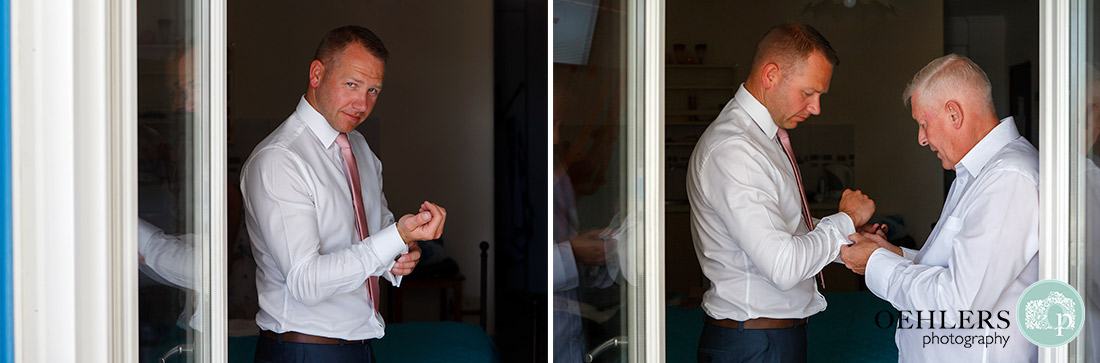 Groom putting on his cufflinks with dad helping him.