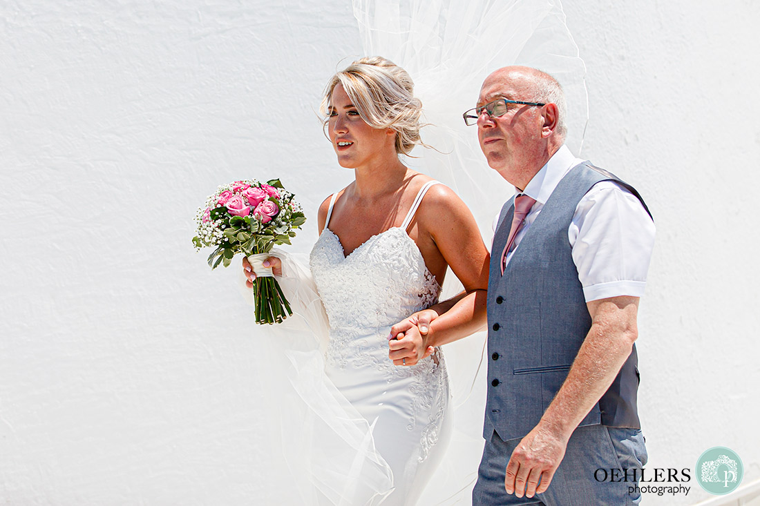 Santorini Destination Wedding Photographers - bride and dad walking eagerly towards the groom.