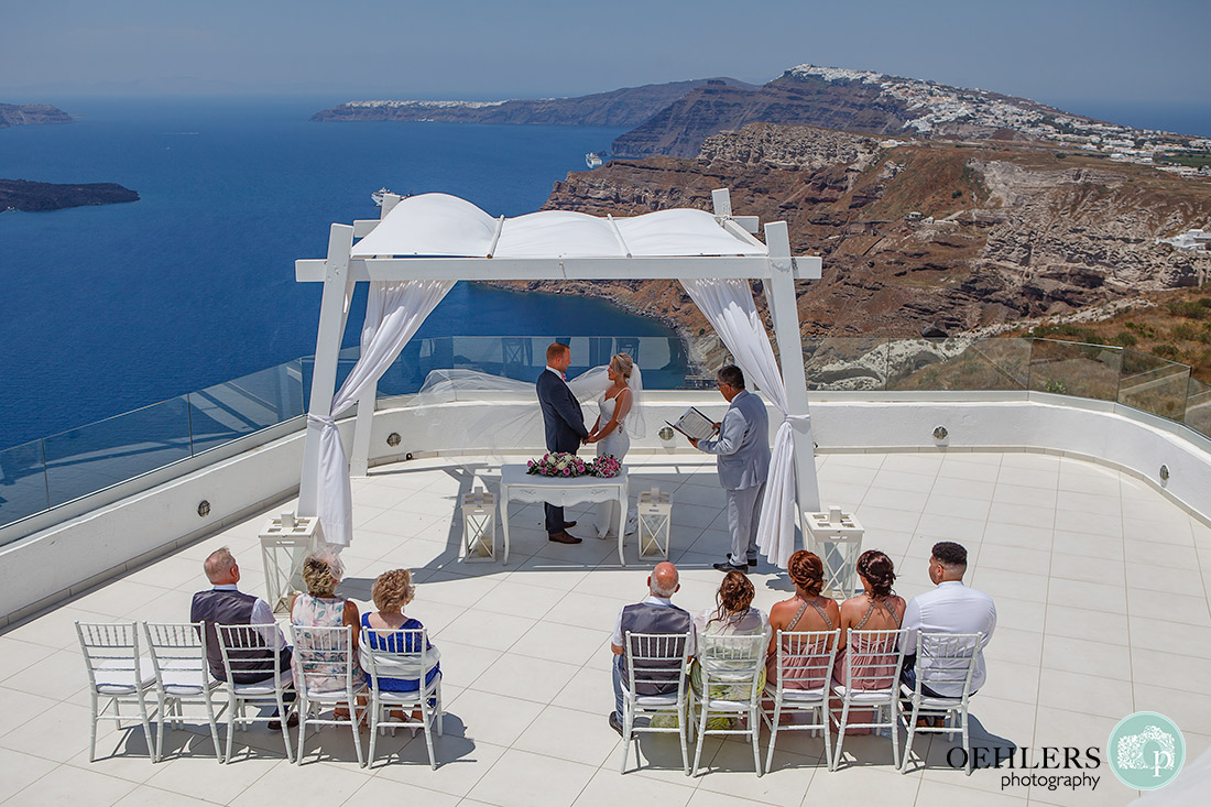 Santorini Destination Wedding Photographers - wow what a backdrop to the ceremony area of the caldera and Aegean Sea.