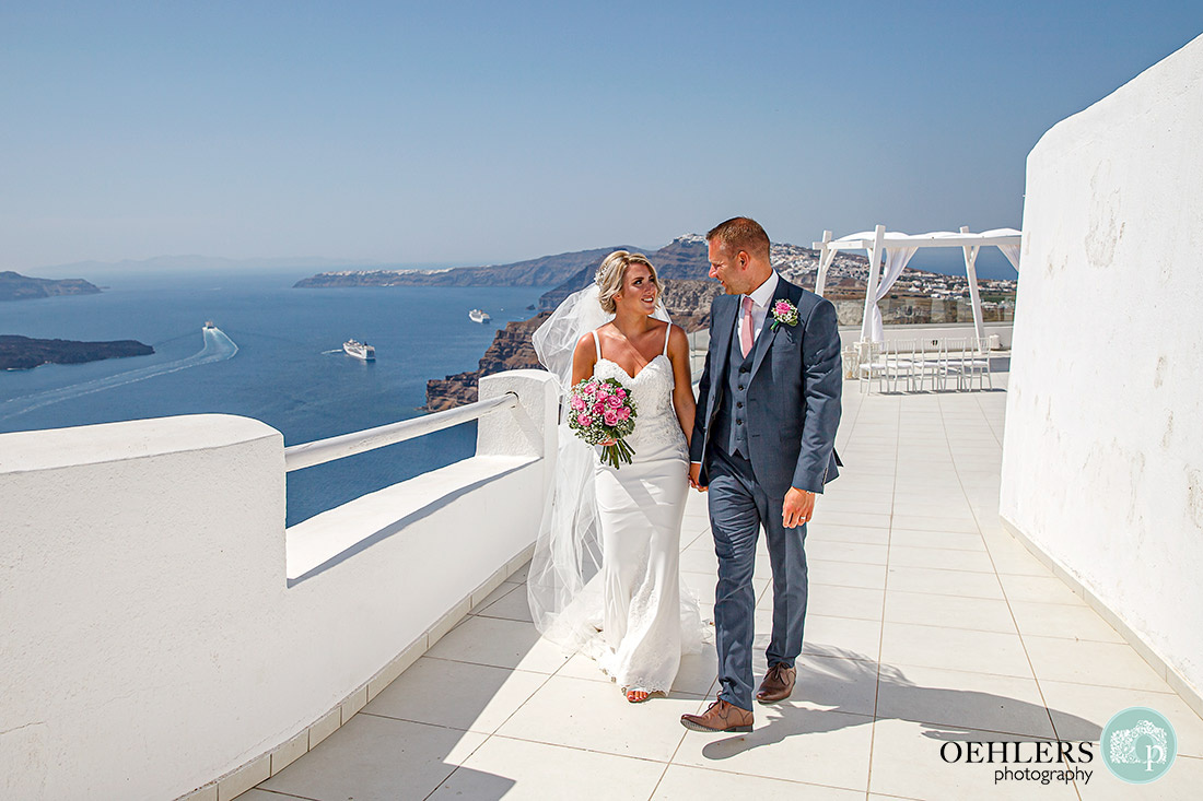 Bride and Groom walking hand in hand away from the ceremony area with backdrop of the Aegean Sea.