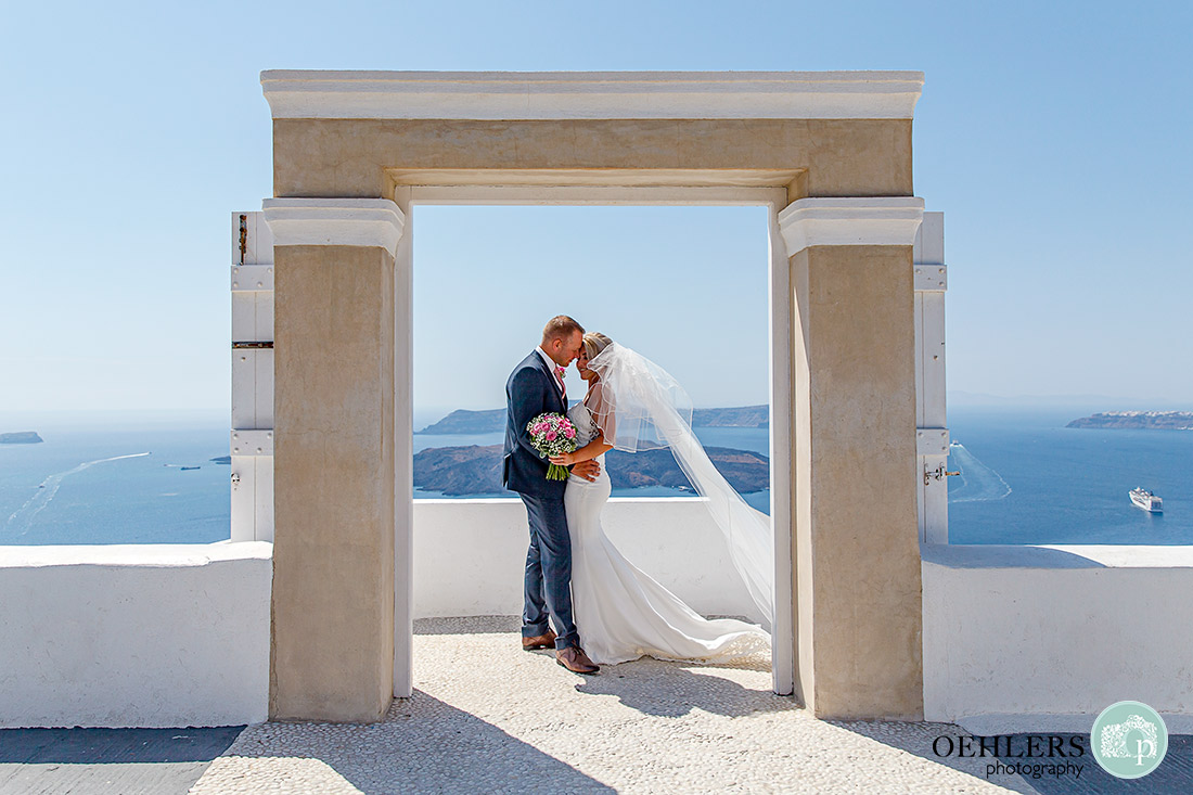 Destination Wedding Photographers - Santorini - bride and groom in a doorway with lovely view behind.