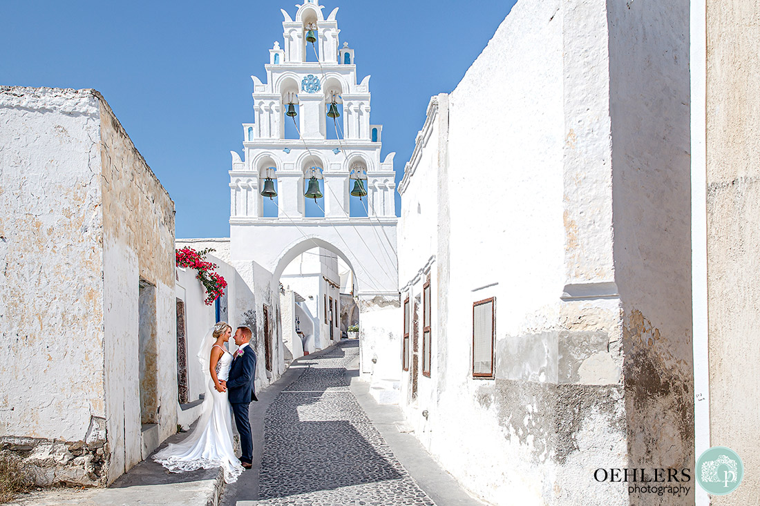 Romantic photograph of bride and groom in front of a bell tower in Megalochiri.