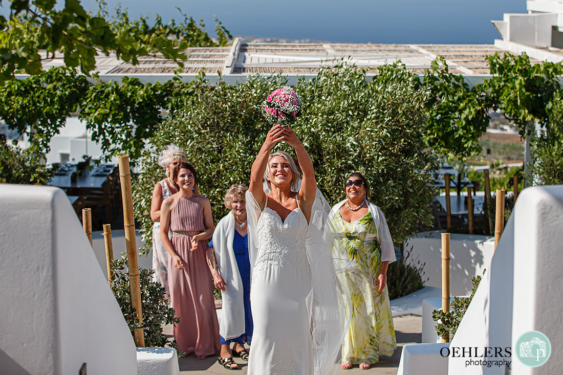 Destination Wedding Photographers - Santorini - bride about to throw the wedding bouquet at Pyrgos Restaurant.