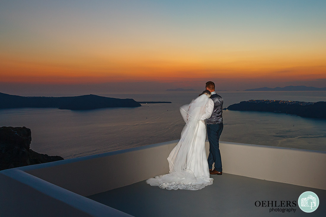 Bride and Groom on a roof top looking out to sea with the beautiful sunset.