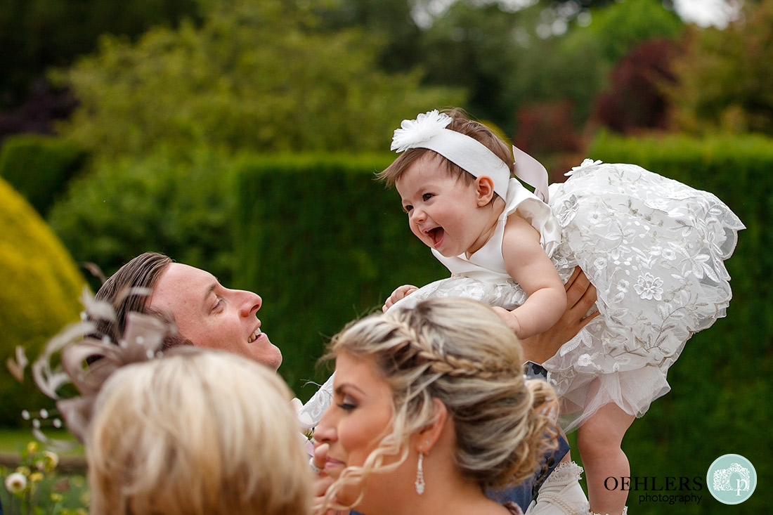 Stoke Rochford Wedding Photographer-Dad lifting the flower girl up.