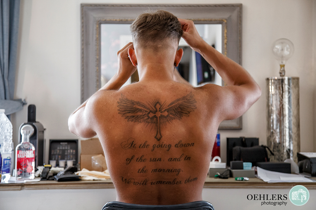 Osmaston Park wedding photography - Groom with quote written on his back whilst looking into a mirror.