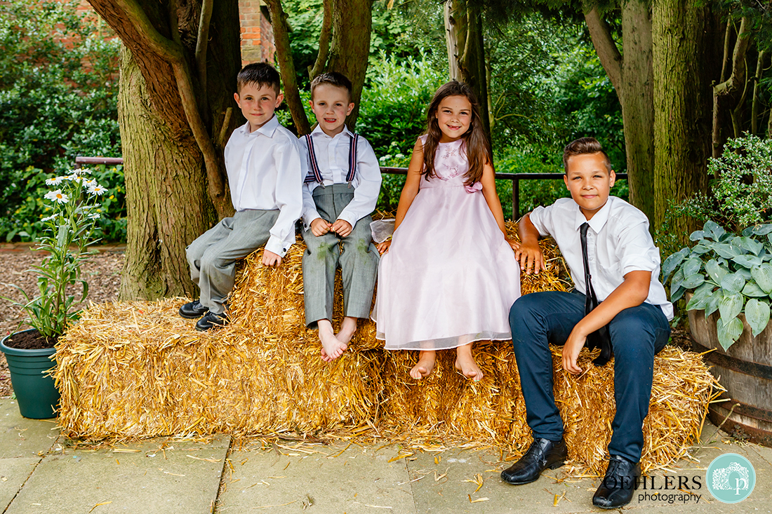 Four cute children sitting and posing on hay bales
