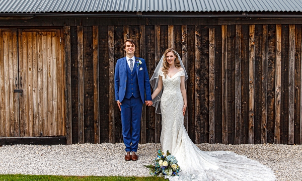 bride and groom in front of a barn
